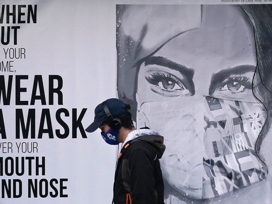 A pedestrian wearing a mask walks past a mural during the coronavirus outbreak in San Francisco.