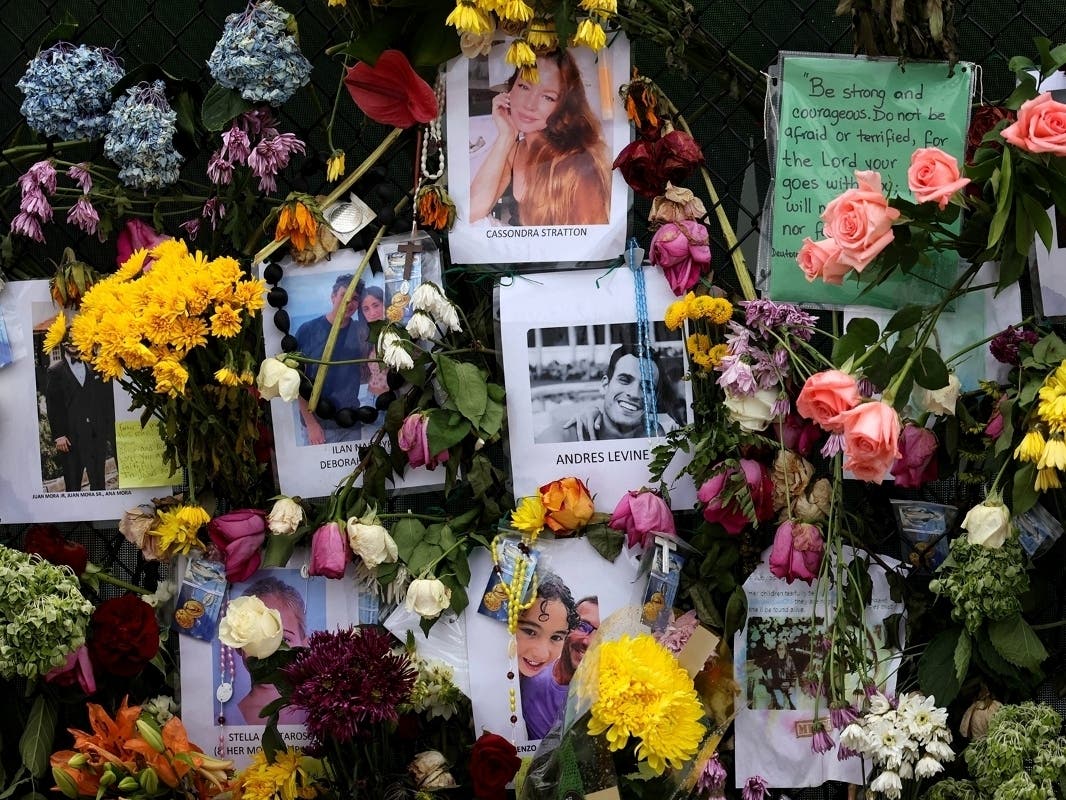Photographs of victims hang on a memorial wall along a fence near the site at the Champlain Towers South condo in Surfside. The building partially collapsed June 24 and the remaining condo tower was demolished Sunday night.