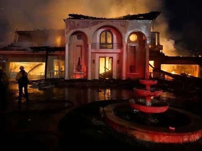 A firefighter works to put out a structure burning during a wildfire Wednesday, May 11, 2022, in Laguna Niguel, Calif.