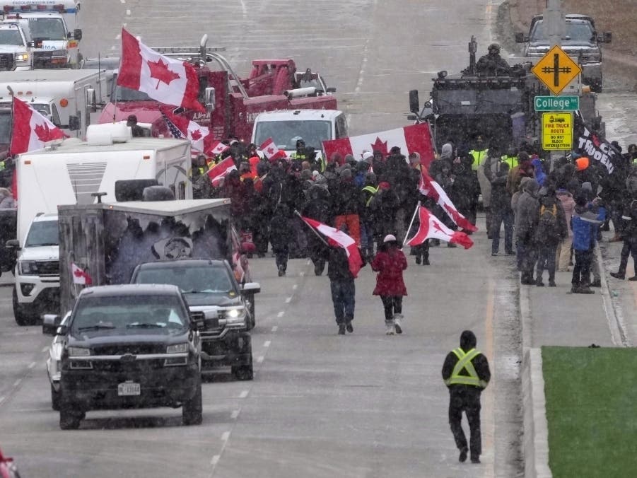 Protesters face police officers as they enforce an injunction against their demonstration, which has blocked traffic across the Ambassador Bridge by protesters against COVID-19 restrictions, in Windsor, Ontario, Saturday.