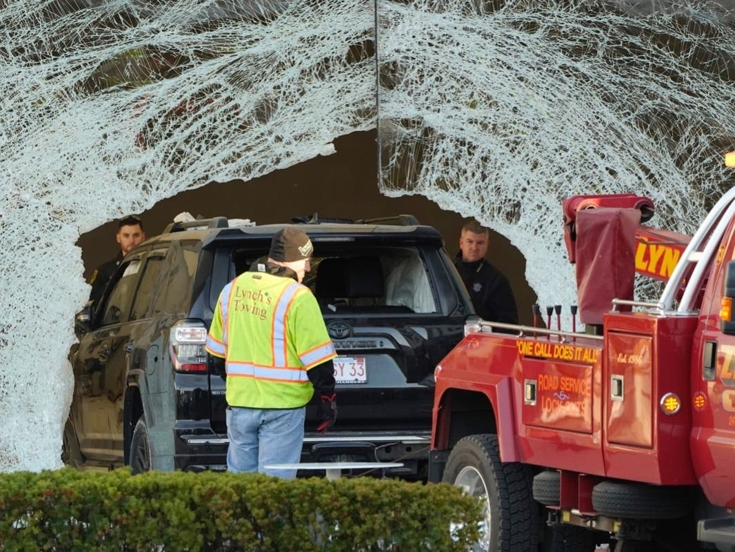 Worker use a tow truck to remove a damaged SUV from inside an Apple store, Monday, Nov. 21, 2022, in Hingham, Mass.