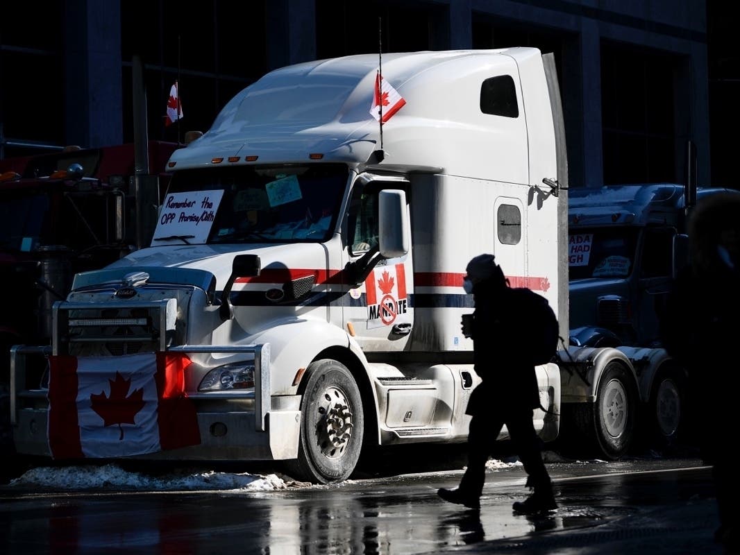 A pedestrian crosses the street near a big rig parked on Metcalfe Street as a protest against COVID-19 restrictions that has been marked by gridlock and the sound of truck horns continues into its second week in Ottawa on Monday, Feb. 7.
