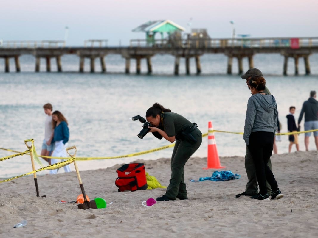 Investigators on the beach in Lauderdale-by-the-Sea, Florida, take photos of the scene of a sand collapse on Tuesday, Feb. 20, 2024. A 7-year-old girl was buried in sand and died Tuesday when a deep hole she was digging collapsed on her.