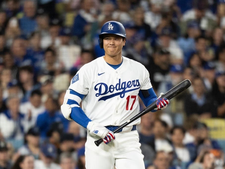 Los Angeles Dodgers' Shohei Ohtani smiles towards the Cleveland Guardians dugout during the first inning of a baseball game in Los Angeles, Tuesday, March 31, 2026.