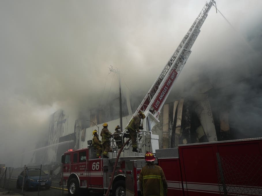 Firefighters work from a ladder truck while fighting a warehouse fire in the Boyle Heights neighborhood of Los Angeles, Sunday, June 21, 2026.