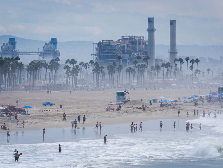 Beachgoers stand in thick humidity as large waves from Tropical Storm Marie break on the shore on Monday in Huntington Beach.