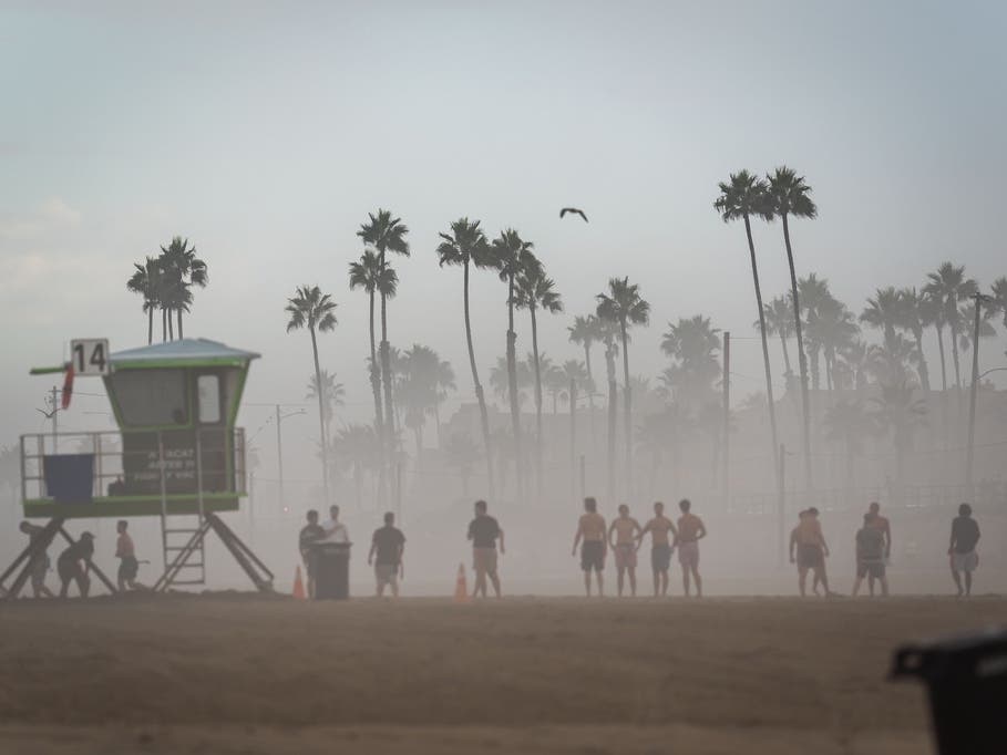 Beachgoers stand in thick humidity brought by Tropical Storm Marie on Monday in Huntington Beach.