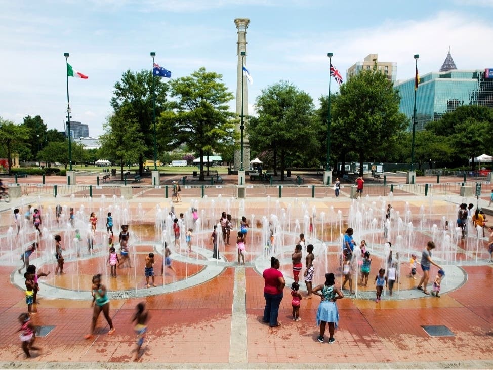 In this Friday, July 22, 2016 photo, people play in the fountains shaped by the Olympic rings at Centennial Olympic Park in Atlanta.