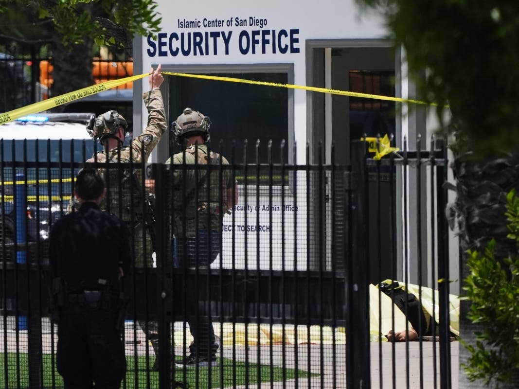 A body is covered with a tarp at the scene of a shooting outside the Islamic Center of San Diego Monday, May 18, 2026, in San Diego.
