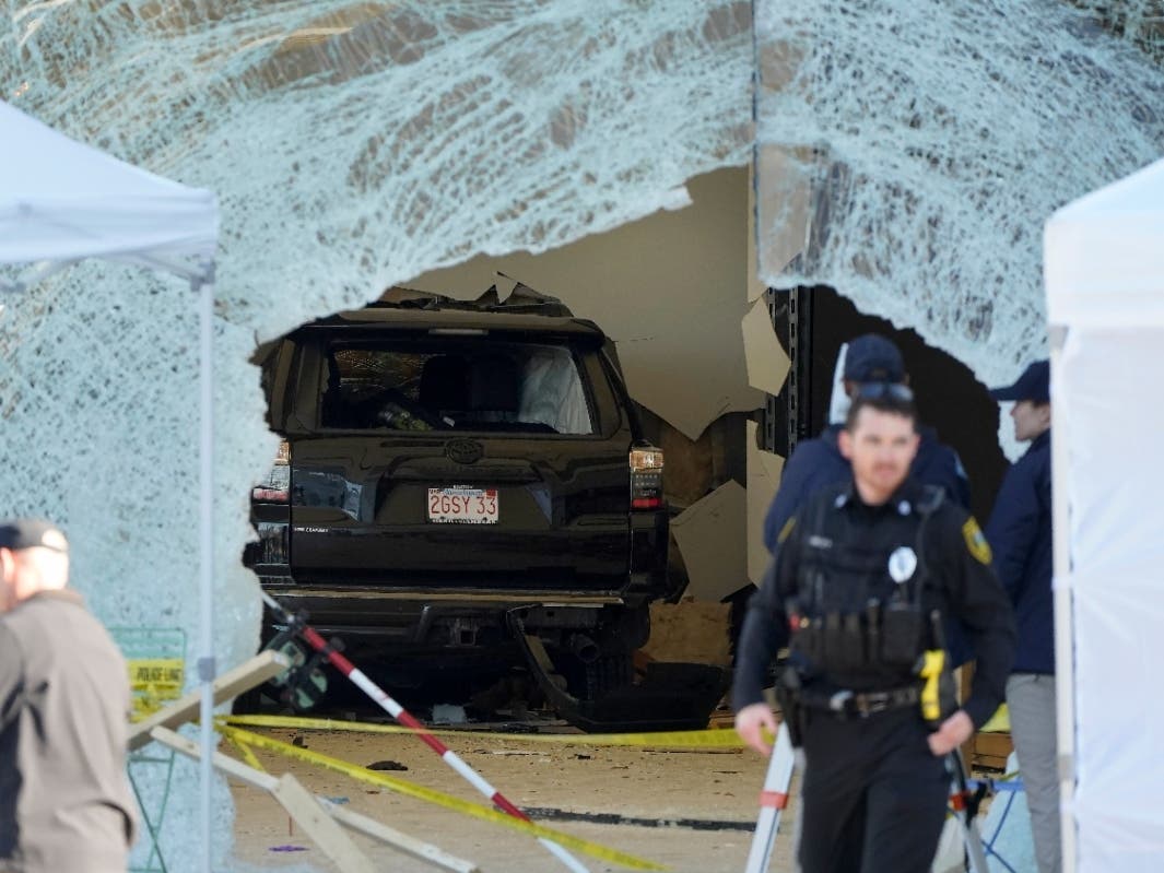 Worker useda tow truck to remove a damaged SUV from inside an Apple store, Monday, Nov. 21, 2022, in Hingham, Mass. At least one person was killed, and multiple others were injured Monday when the SUV crashed into the store, authorities said.