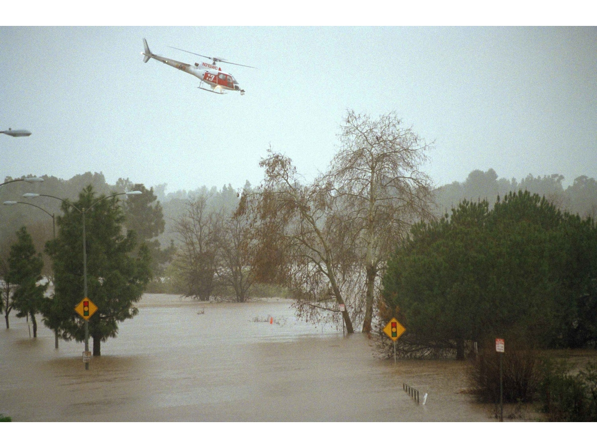 A Los Angeles County fire department helicopter flys over a flooded street in Burbank, Calif., searching for any possible stranded motorists, Tuesday, Feb. 3, 1998. An El Nino-charged storm clobbered Southern California on Tuesday with drenching rains.