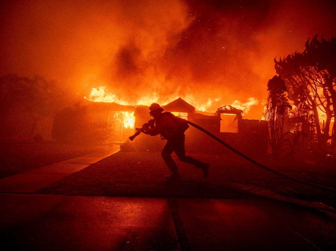 A firefighter battles the Palisades Fire as it burns a structure in the Pacific Palisades neighborhood of Los Angeles on Jan. 7, 2025.