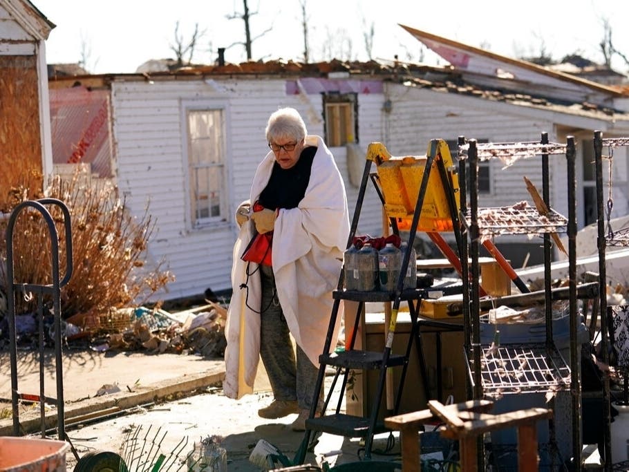Martha Thomas stays warm with a bed comforter as volunteers help her salvage possessions from her destroyed home in the aftermath of tornadoes that tore through the region, in Mayfield, Ky., Monday, Dec. 13, 2021. 