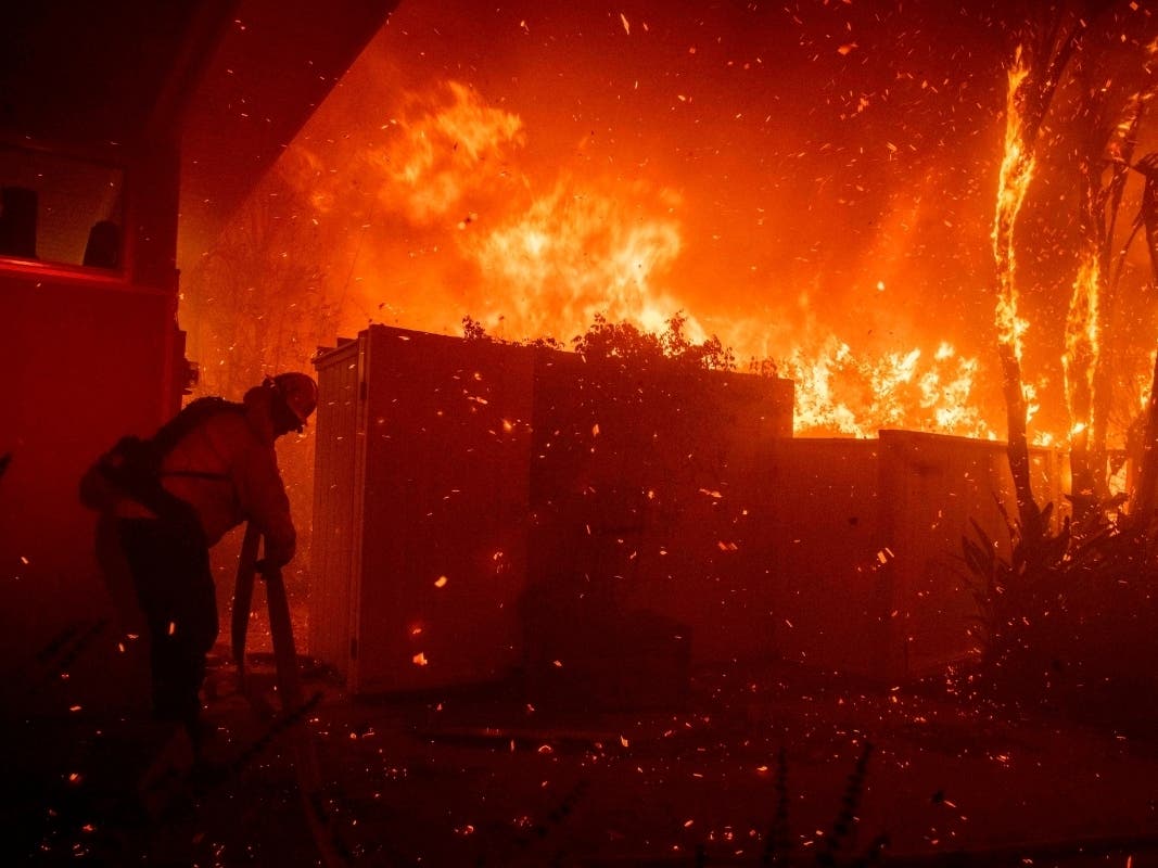 Firefighters try to save a home from a wildfire on Tigertail Road on Monday in Los Angeles.