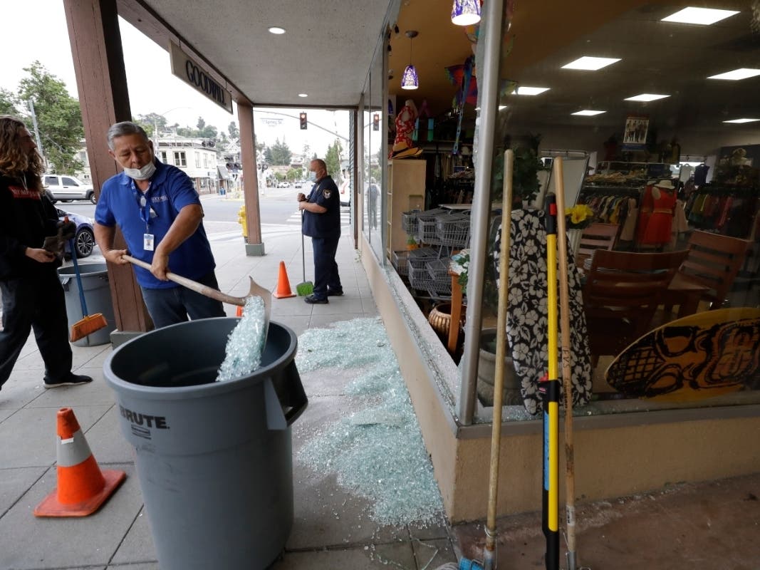 Workers clean up glass from a broken window at a Goodwill store after a protest over the death of George Floyd, Sunday, May 31, 2020, in La Mesa, Calif.