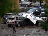 A woman walks by cars damaged by floods during a rainstorm in San Diego on Monday, Jan. 22, 2024.