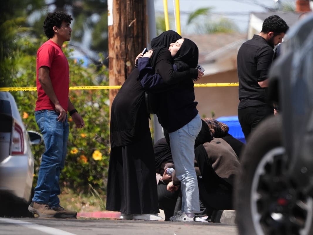 People embrace near the scene of a shooting outside the Islamic Center of San Diego Monday, May 18, 2026, in San Diego.