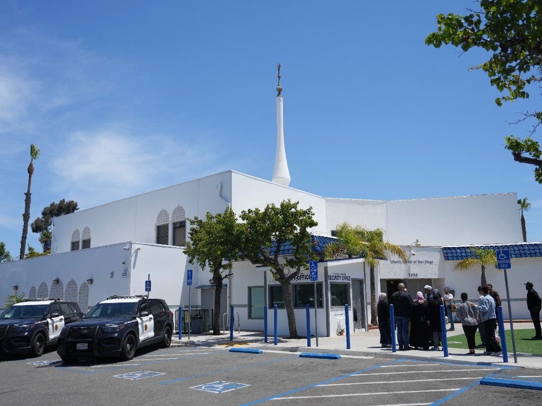 People gather as police vehicles are parked outside of the Islamic Center of San Diego, the day after a shooting, May 19, 2026, in San Diego.