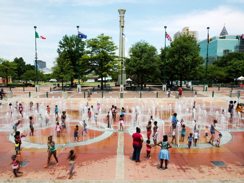 In this Friday, July 22, 2016 photo, people play in the fountains shaped by the Olympic rings at Centennial Olympic Park in Atlanta.