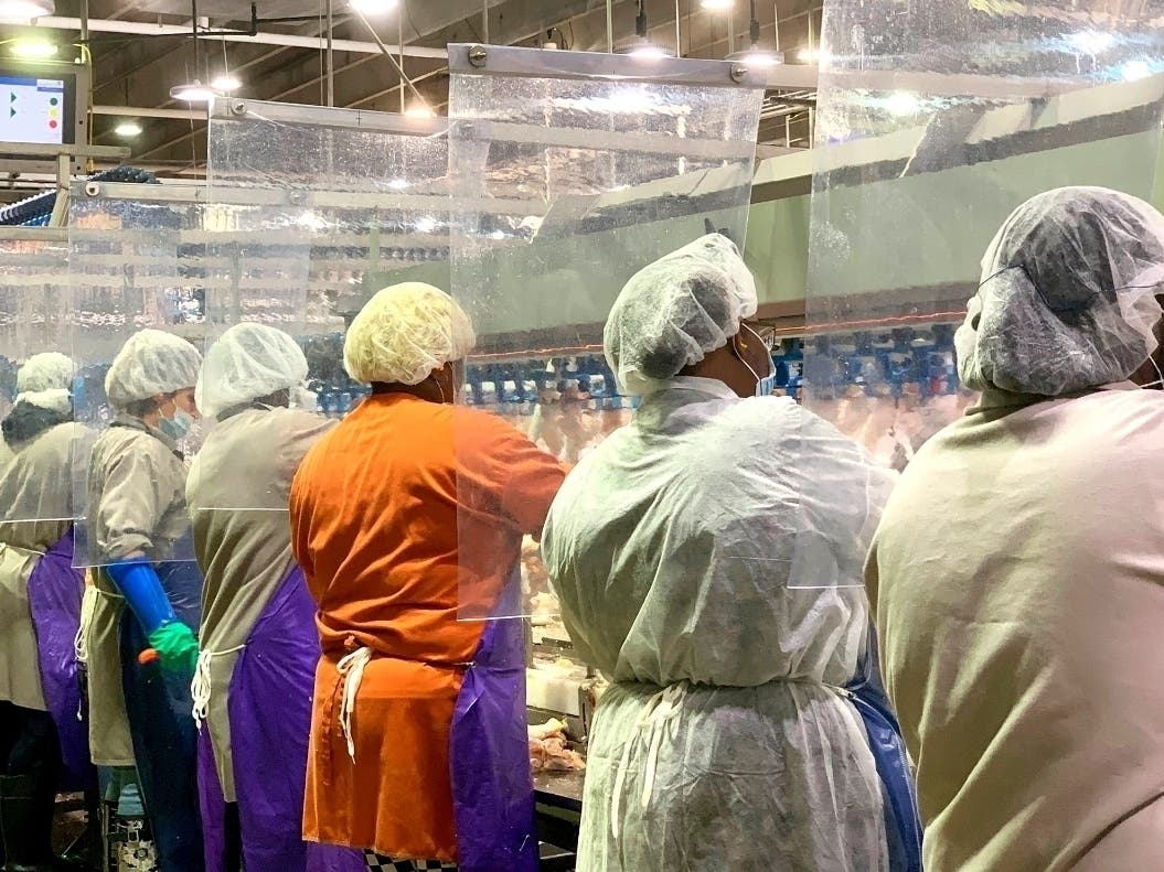 Tyson Foods workers wear protective masks and stand between plastic dividers at the company's Camilla, Georgia poultry processing plant. 