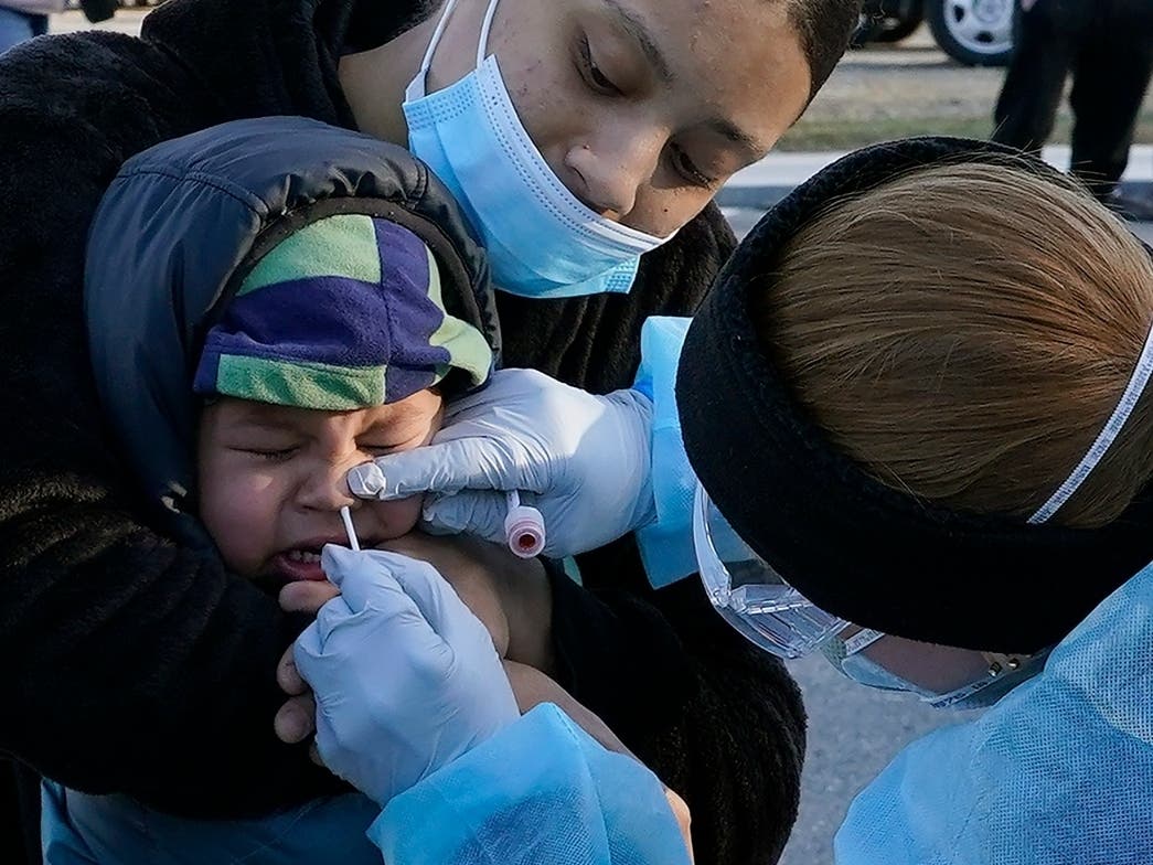 Jamillette Gomes holds her 2-year-old son, Avian, as he receives a COVID-19 virus test in Lawrence, Mass. 