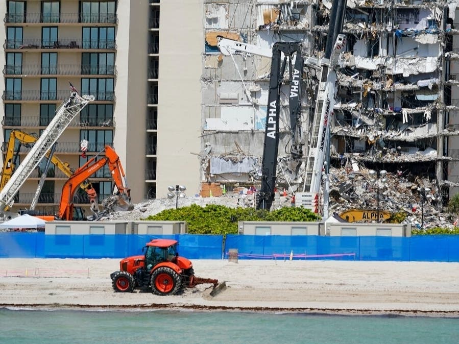 A plow maintains the beach out front as search and rescue personnel work atop the rubble at the Champlain Towers South condo building, where scores of people remain missing one week after it partially collapsed.