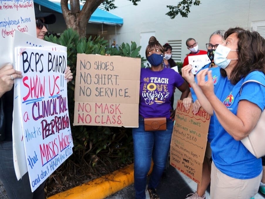 A teacher tries to persuade an anti-mask protester that all students need to wear masks to protect the most vulnerable during a protest outside of a Broward County School Board meeting in Florida. 
