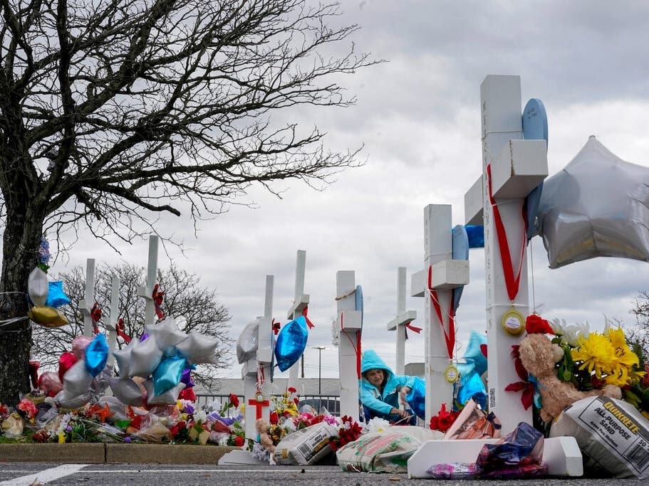 A woman ties balloons to a cross in a makeshift memorial in the parking lot of a Walmart in Chesapeake on Monday for the six people killed in a Nov. 22 shooting.