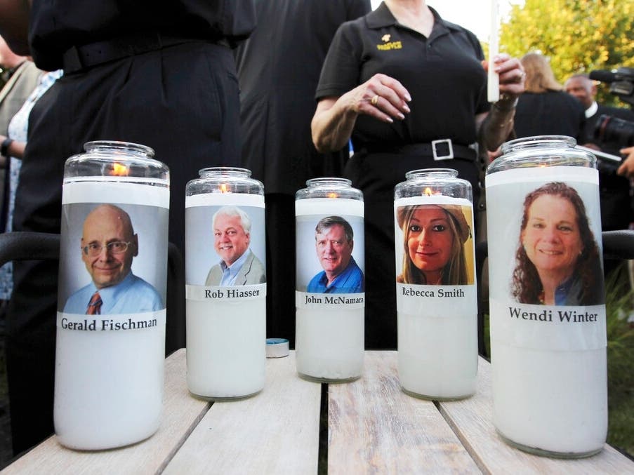 Photos of five employees of the Capital Gazette newspaper adorn candles during a vigil, June 29, 2018, across the street from where they were slain in the newsroom in Annapolis, Maryland.