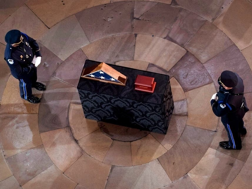 An honor guard stands before a ceremony memorializing U.S. Capitol Police officer Brian Sicknick, as an urn with his cremated remains lies in honor on a black-draped table at the center of the Capitol Rotunda.