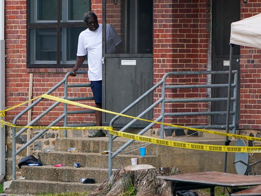 A person looks out the front door of a home as police tape surrounds the area of a mass shooting in the Brooklyn Homes area of Baltimore on July 2.