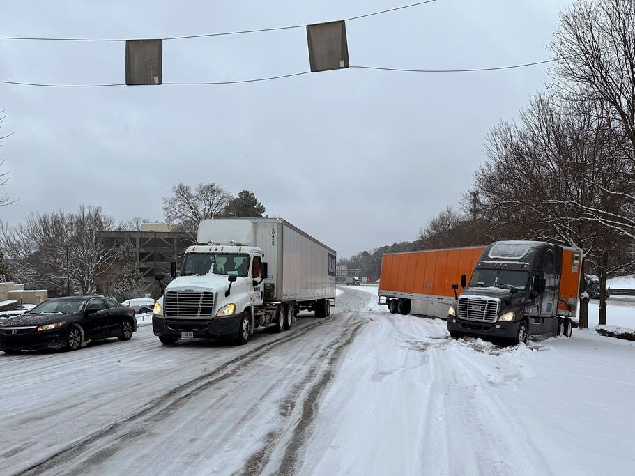 A truck is jackknifed as another spins its wheels on a slushy offramp off Interstate 285 northeast of downtown Atlanta on Friday.