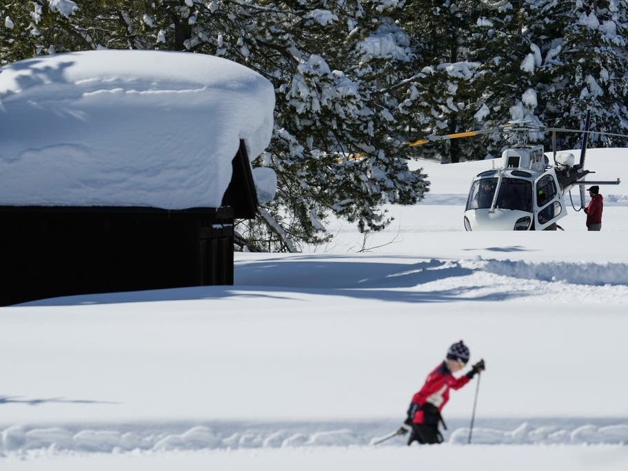 A skier goes past a California Highway Patrol search crew in the aftermath of a snowstorm on Friday in Truckee.