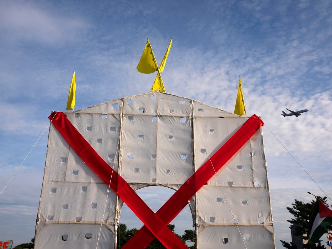 A plane flies over an anti-arch structure, lifted by demonstrators at Memorial Circle to protest the proposed Triumphal Arch, in Arlington on Thursday, Oct. 1, 2026.