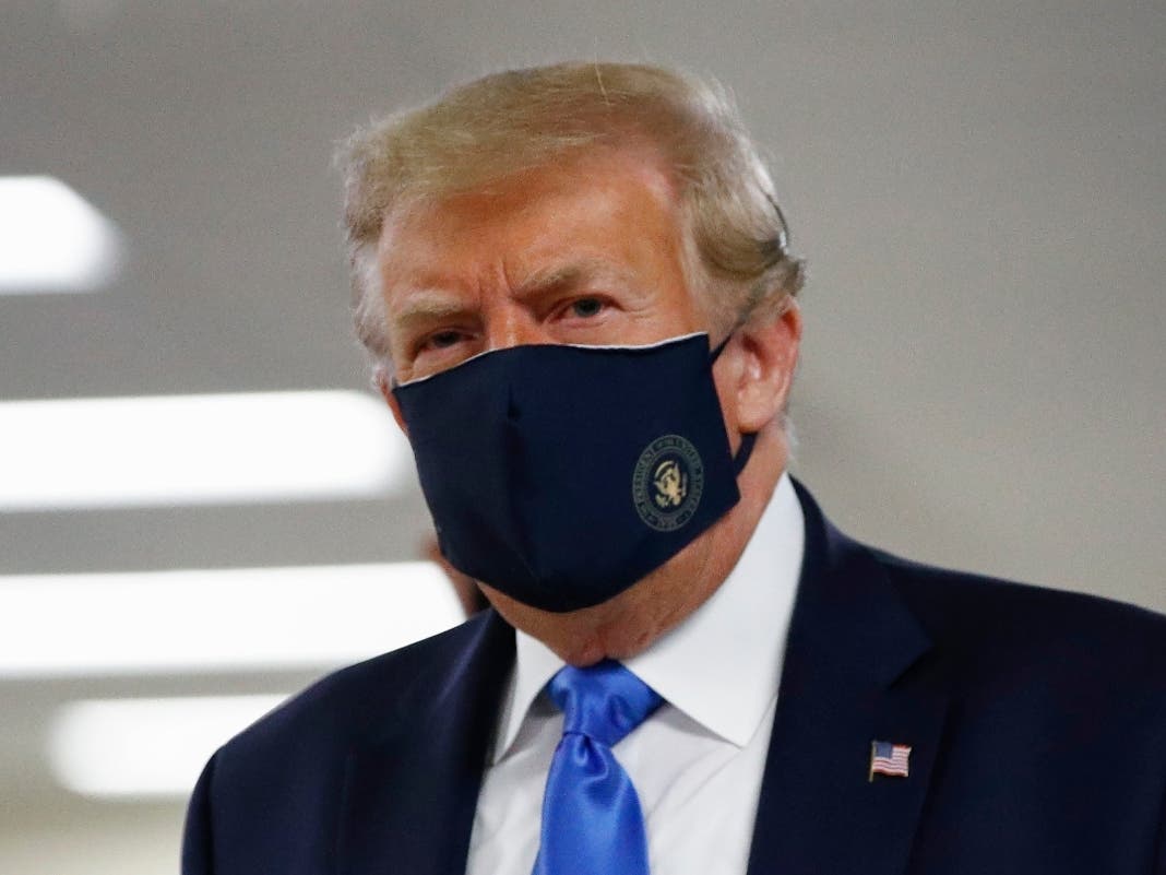President Donald Trump wears a face mask as he walks down a hallway during a visit to Walter Reed National Military Medical Center in Bethesda on Saturday, July 11.