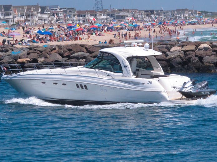 A yacht cruises through the Manasquan Inlet as a large crowd fills the beach in Manasquan, N.J. on June 28, 2020. 