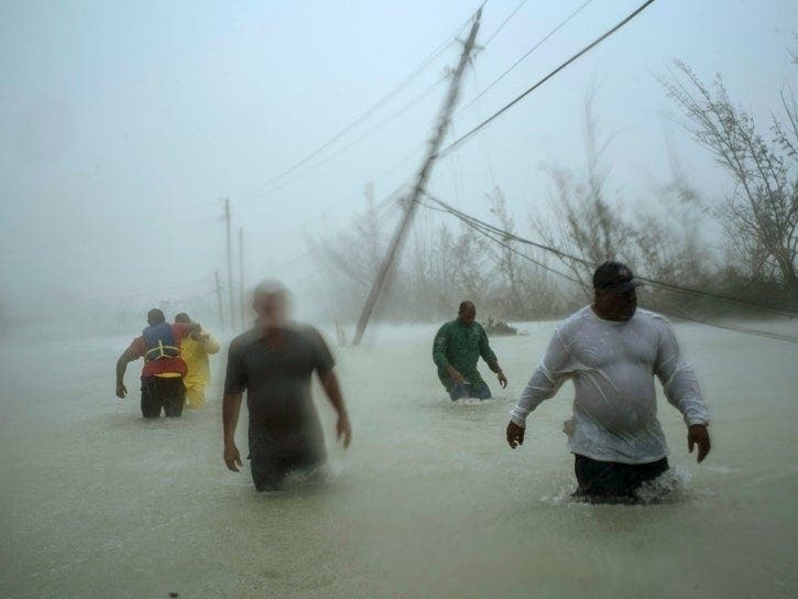 Volunteers walk under the wind and rain of Hurricane Dorian near a bridge in Freeport, Grand Bahama, Bahamas, Tuesday, Sept. 3, 2019. 