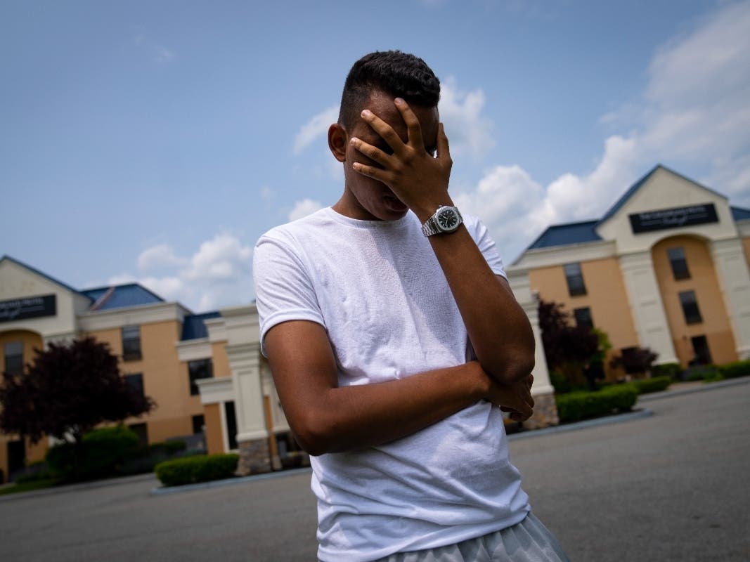Mohamed, a 19-year-old fleeing political persecution in Mauritania, obscures his face to protect his identity outside the Crossroads Hotel in Newburgh. He is one of about 400 migrants the city has put up in other parts of the state to relieve pressure.