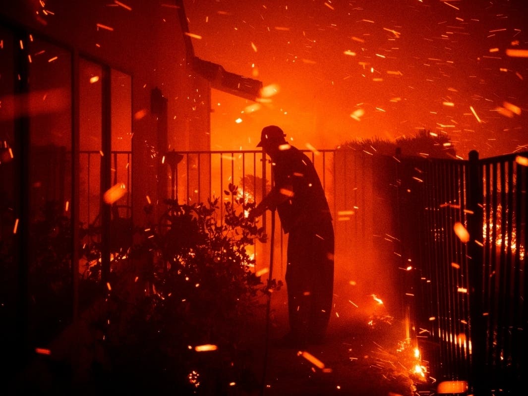 Jerry Rowe uses a garden hose to save his home on Beaufait Avenue from the Saddleridge fire in Granada Hills, California on Friday.