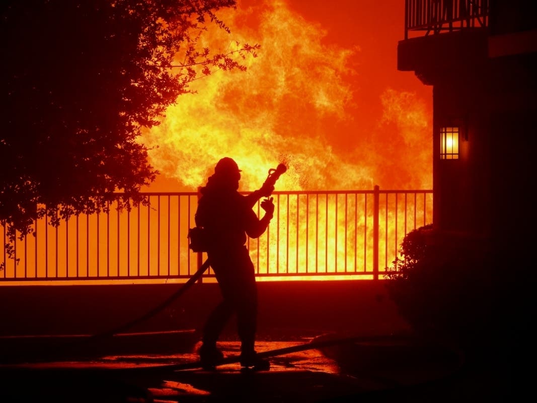 A firefighter waits for water Thursday as the Saddleridge fire flares up near homes in Sylmar, California.