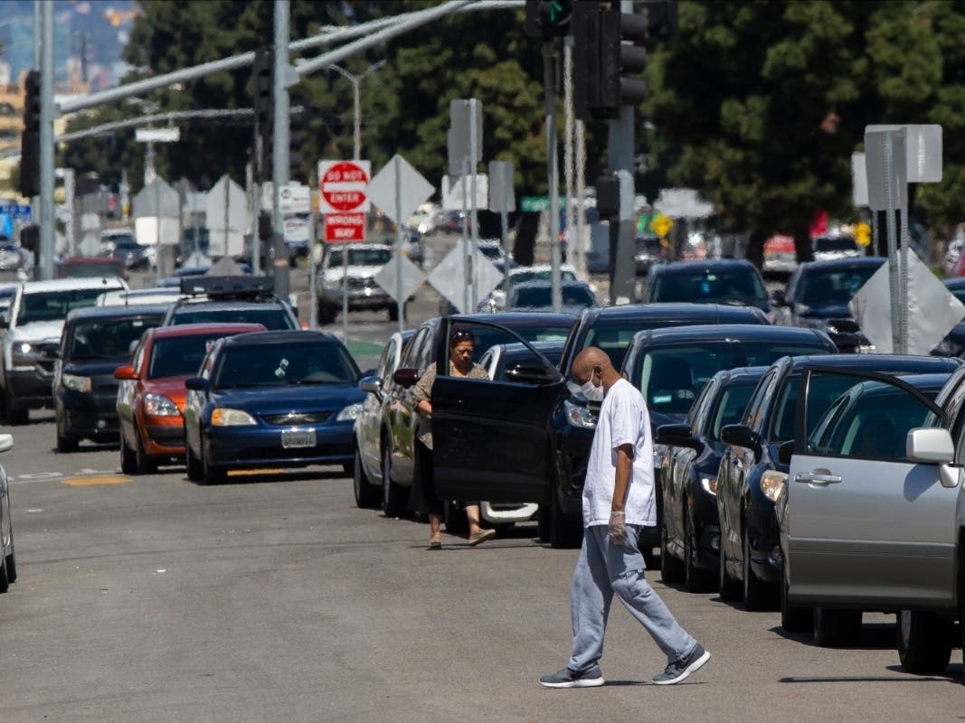 Los Angeles resident Larnell Brown, 66, wears gloves and a mask as he steps out of his waiting vehicle outside the Crenshaw Christian Center before it opens as a testing site for COVID-19 in South Los Angeles.