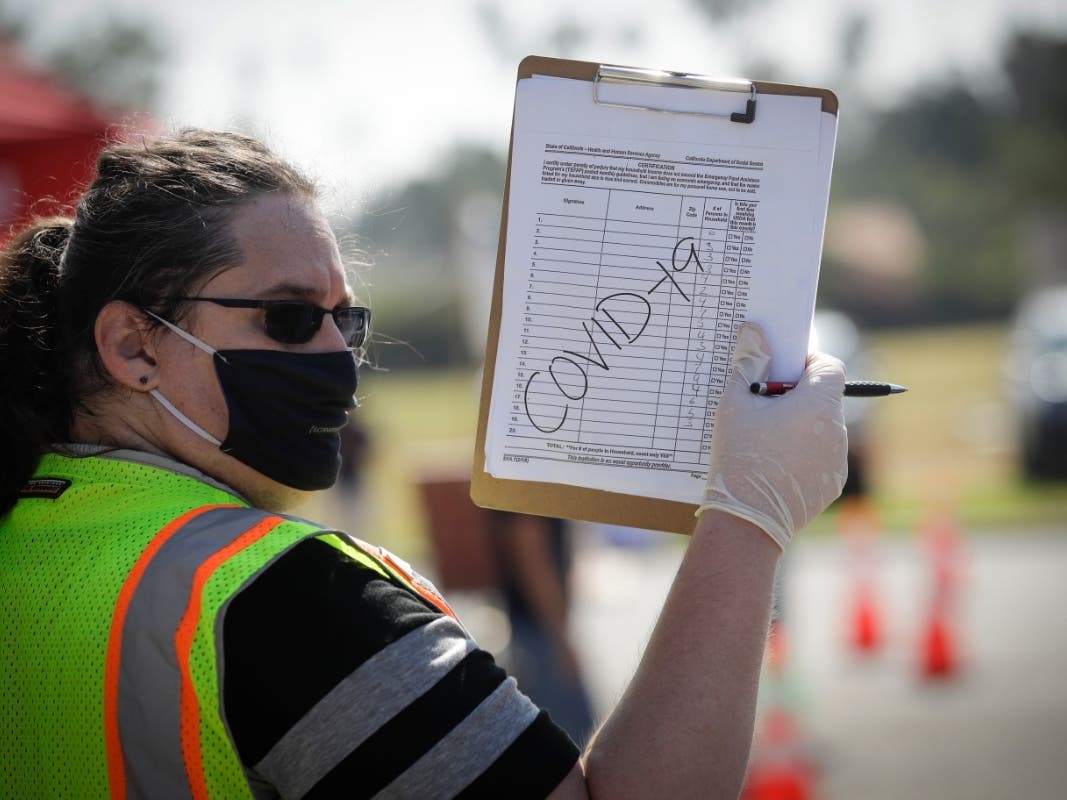 A volunteers directs traffic at a food distribution center Wednesday, July 22, 2020, in the Mission Hills area of Los Angeles.