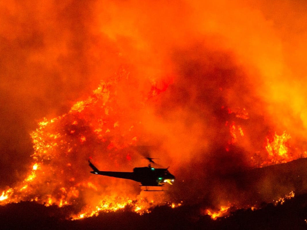 A helicopter prepares to drop water at a wildfire in Yucaipa, Calif., Saturday, Sept. 5, 2020.