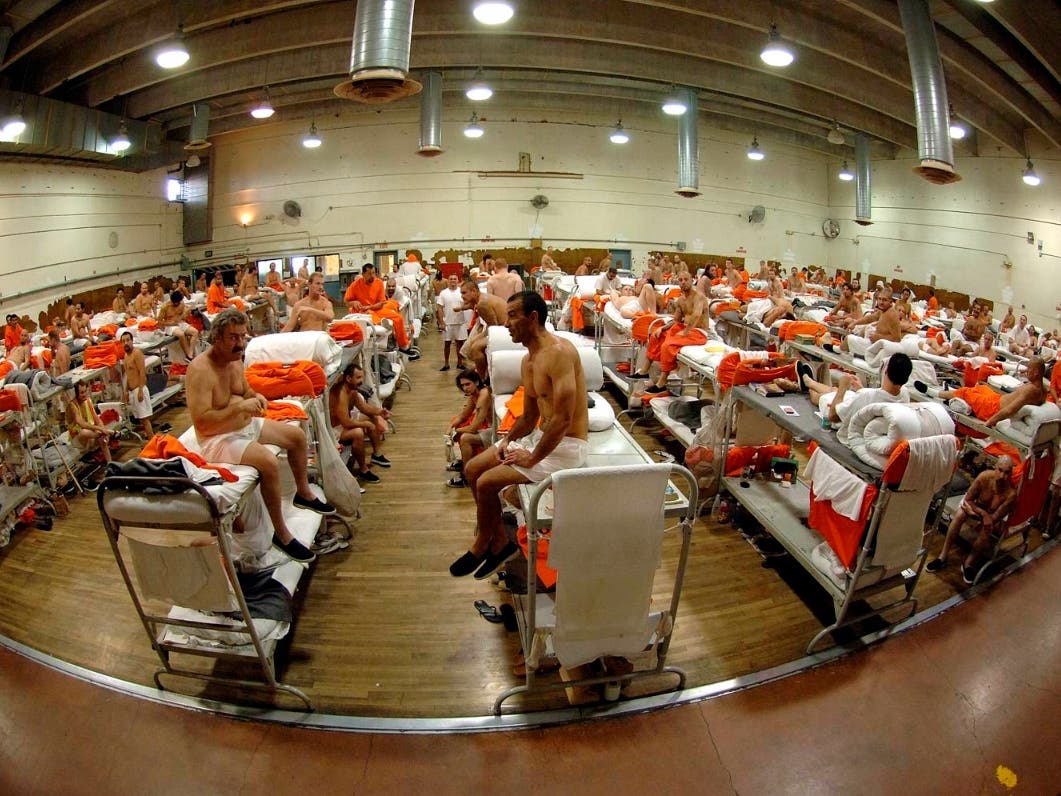 In this undated photo released by the California Department of Corrections, inmates sit in crowded conditions at the California Institute for Men in Chino, Calif. 