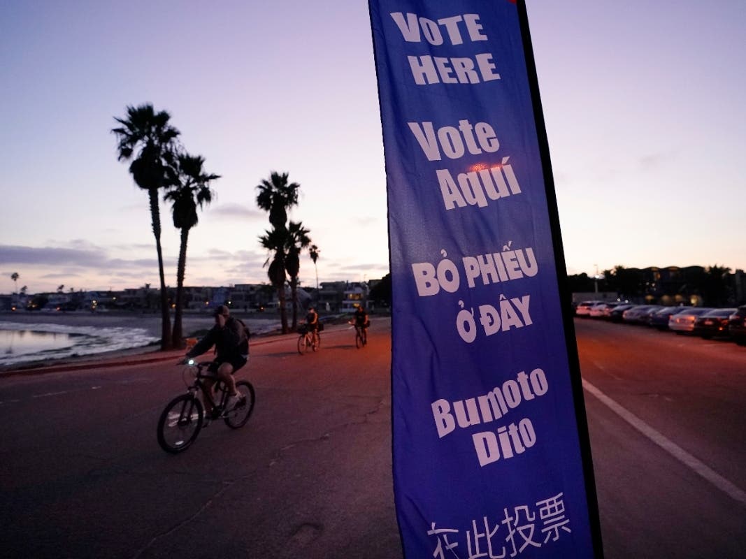 People pass a sign for a polling place on Election Day, Tuesday, Nov. 3, 2020, in San Diego.