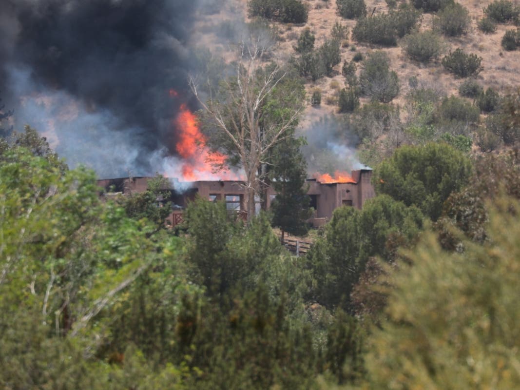 A fire engulfs a house in Acton, Calif., Tuesday, June 1, 2021. Los Angeles County Fire Department supervisor Leslie Lua said paramedics responded to reports of gunshots shortly before 11 a.m. at Fire Station 81.