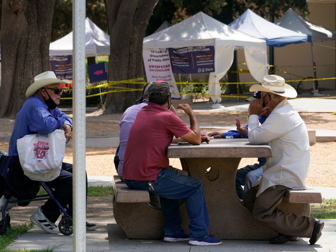 People play cards outside a county-run vaccination site at Eugene A. Obregon Park in Los Angeles, Thursday, July 22. The top health official in Los Angeles County on Thursday implored residents to get vaccinated as the region experiences a COVID-19 surge.