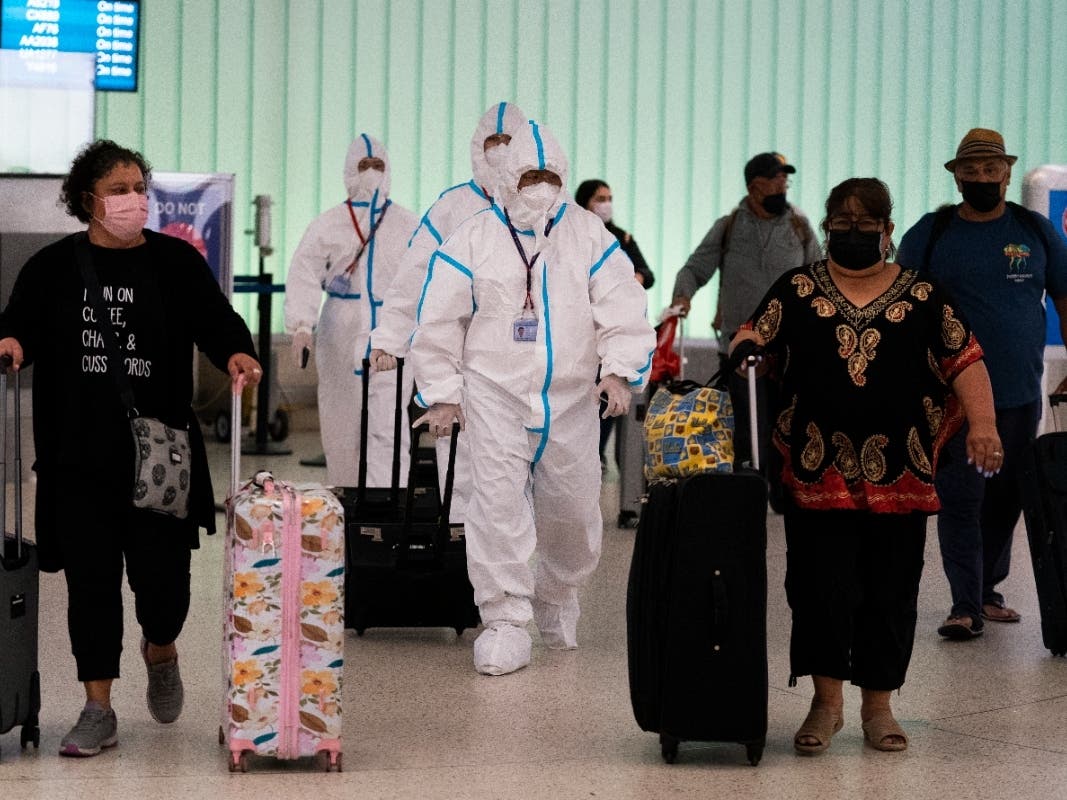 Air China flight crew members in hazmat suits walk through the arrivals area at Los Angeles International Airport in Los Angeles, Tuesday, Nov. 30, 2021.