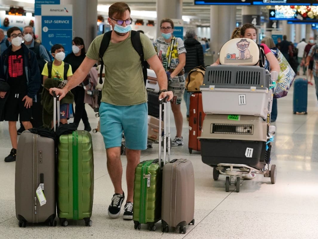 A family and their pets walk through an airport, Monday, Dec. 20, 2021. Public health officials are urging caution as the new omicron variant that became the dominant strain in the U.S. during the holiday break. 