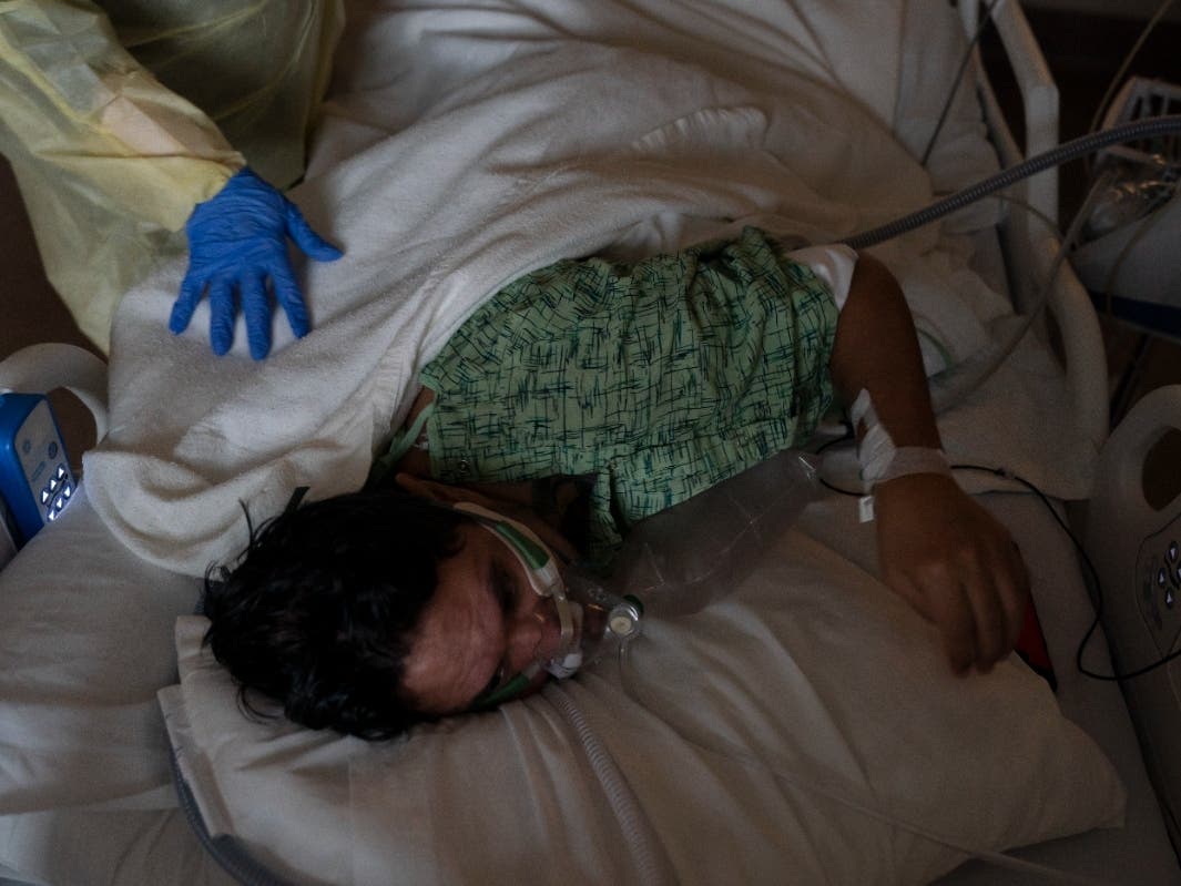 Registered nurse Nvard Termendzhyan helps Julio Valladares, 46, change his position while treating him in a COVID-19 unit at Providence Holy Cross Medical Center in Los Angeles.